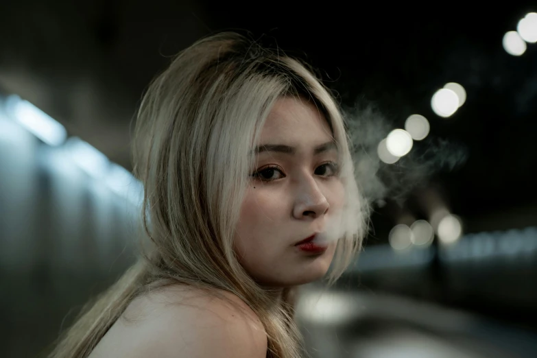 a woman with long blonde hair smoking and staring ahead