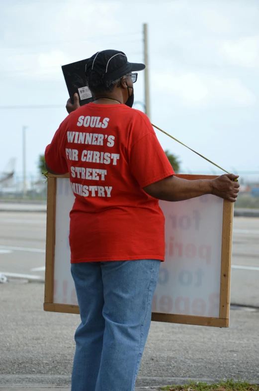 a woman is holding a sign and hat