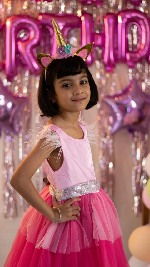 a  in pink and red dress standing in front of balloons