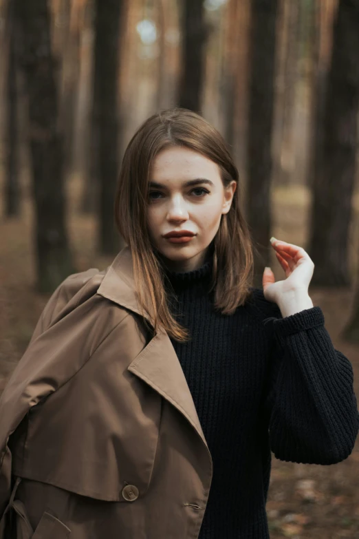 the girl is walking through the woods wearing a jacket