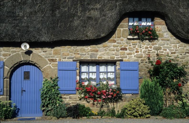 a cute stone house with blue shutters and windows