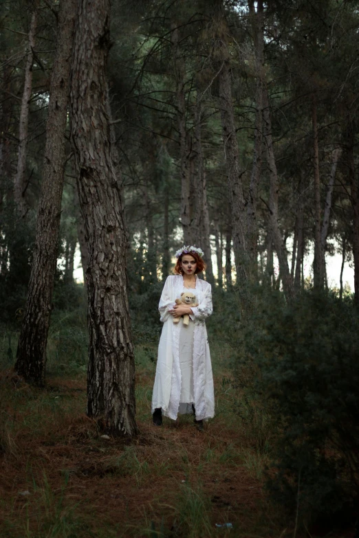 a woman is standing near trees wearing white