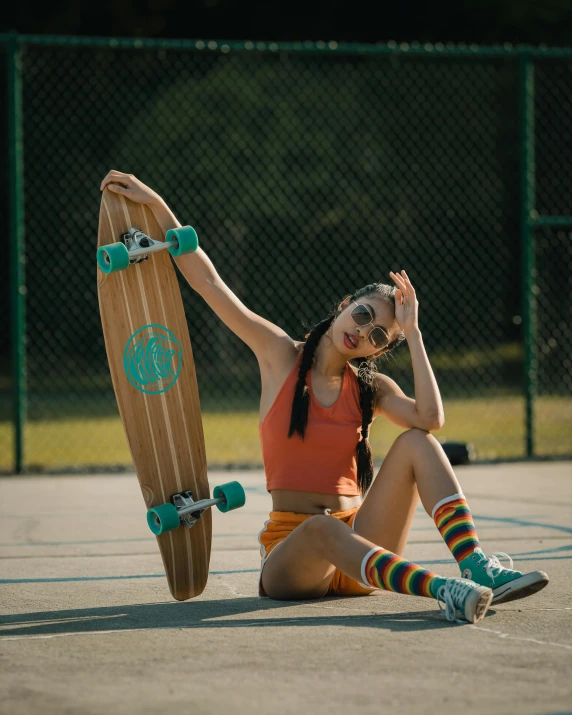 the girl is sitting on the ground with her skateboard