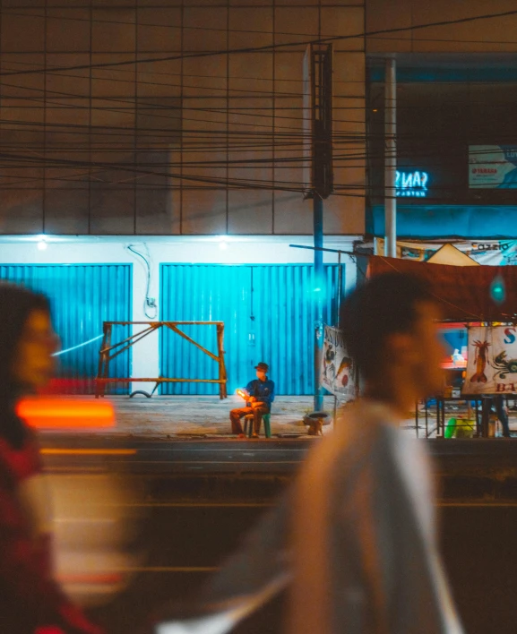 two people standing outside at night in front of a building