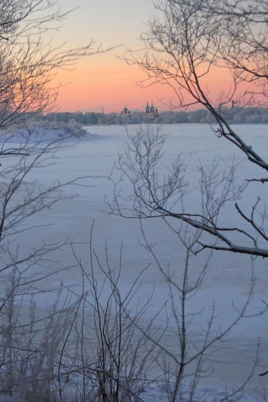 a snowy field with the sun setting in the distance