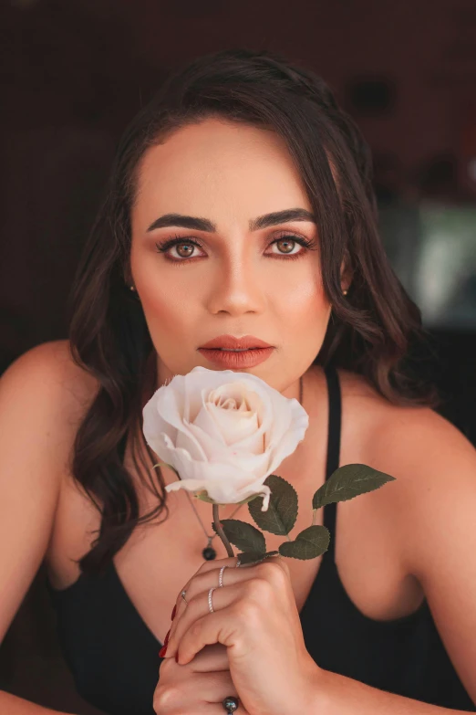 a woman is holding up a rose in her hands