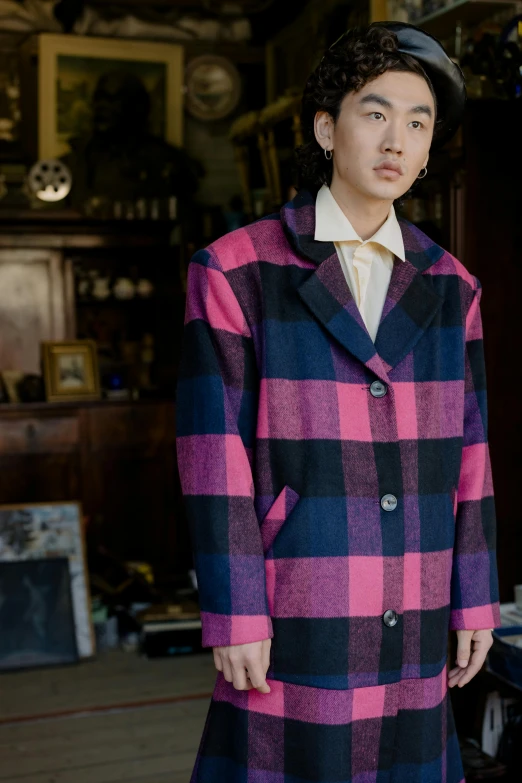 a woman in pink and black plaid coat standing near table