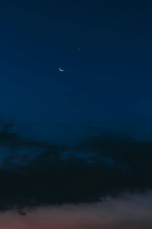 a dark sky with a crescent moon and clouds