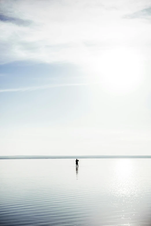 a lone man standing in the middle of a calm ocean