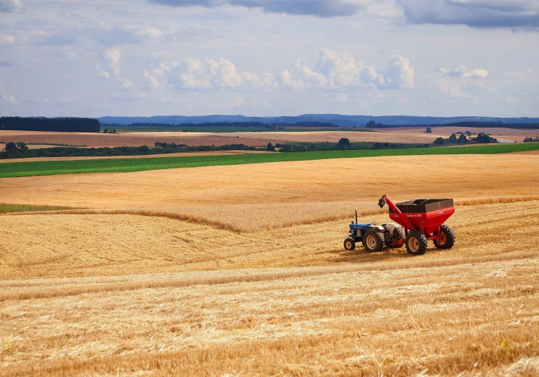 a red tractor driving through a field full of wheat