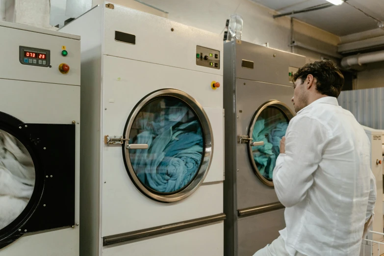 the worker is looking at a front loading washer