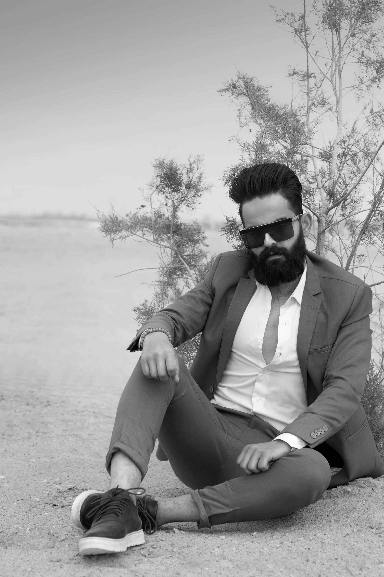 man in sunglasses sitting on the ground by the water