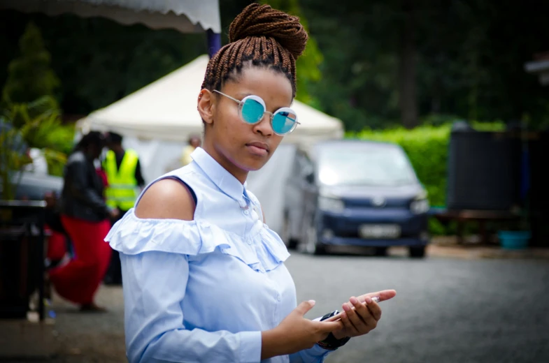 a woman standing outside on her cell phone wearing large round sunglasses