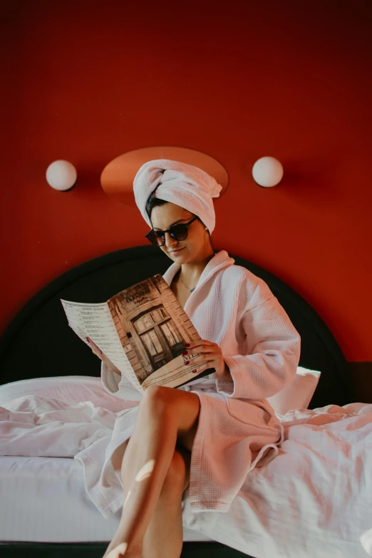 a woman sitting on a bed reading a paper