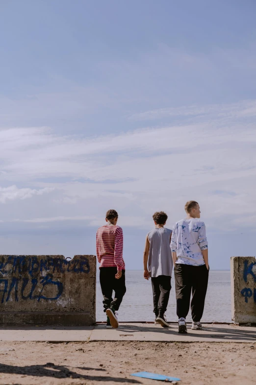 three men walking down a pier with graffiti on them