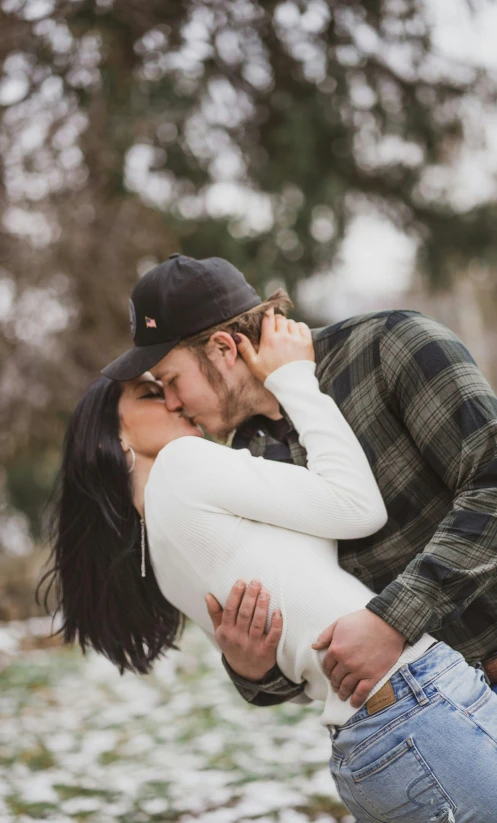 a man and woman kissing under some trees