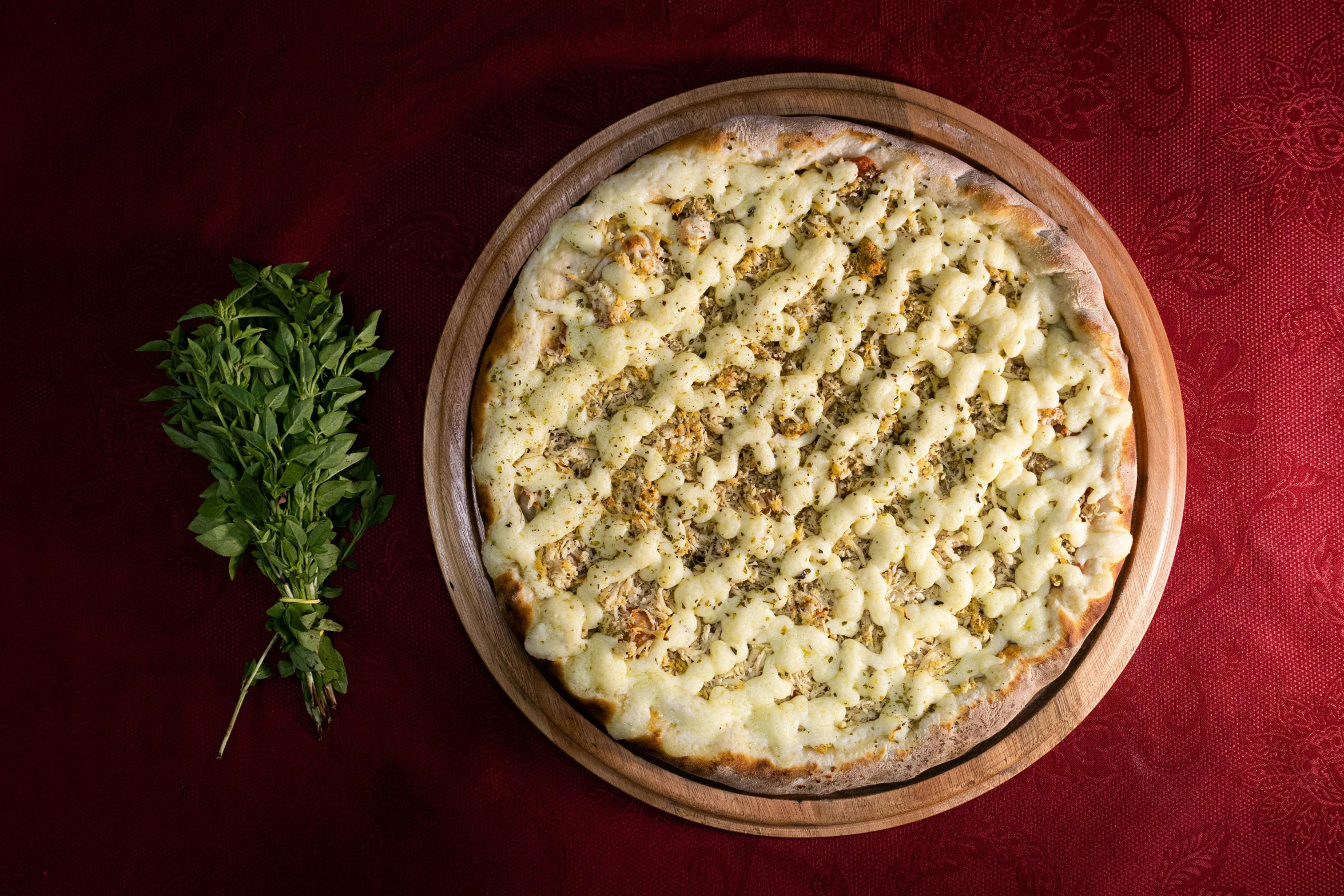 a pizza in a wooden bowl on a red surface