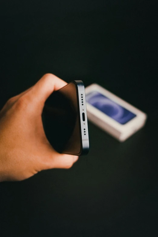 a hand holding a cell phone while next to a white smart phone