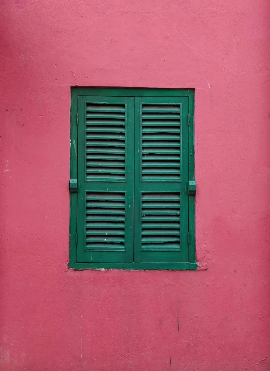 green shutters on the window of a red building