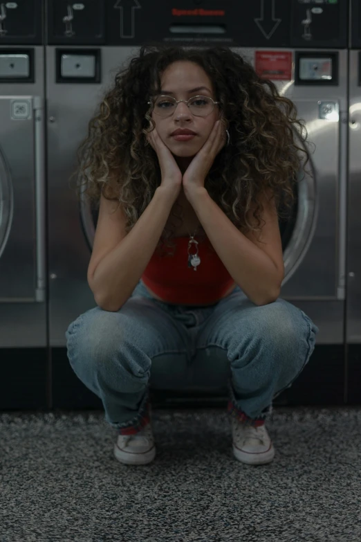 a woman is sitting on the floor next to a dryer