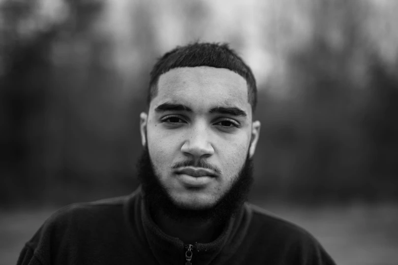 a man with beard and black shirt looking at camera