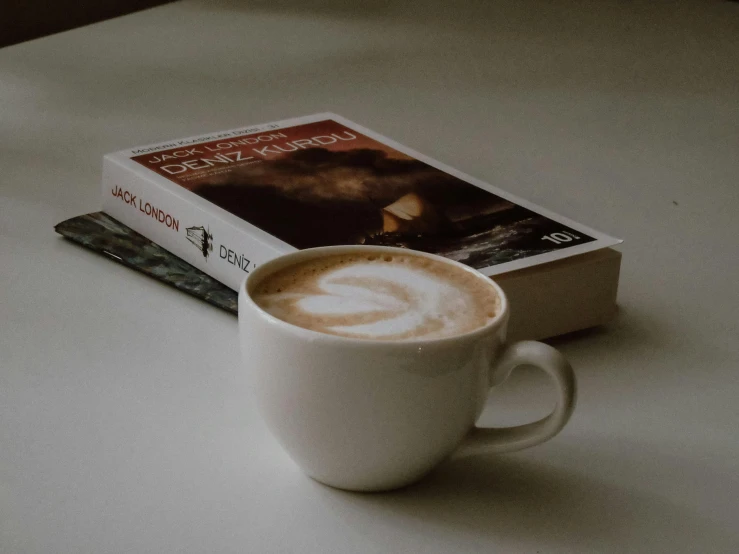 a book and coffee cup sitting next to each other on a table