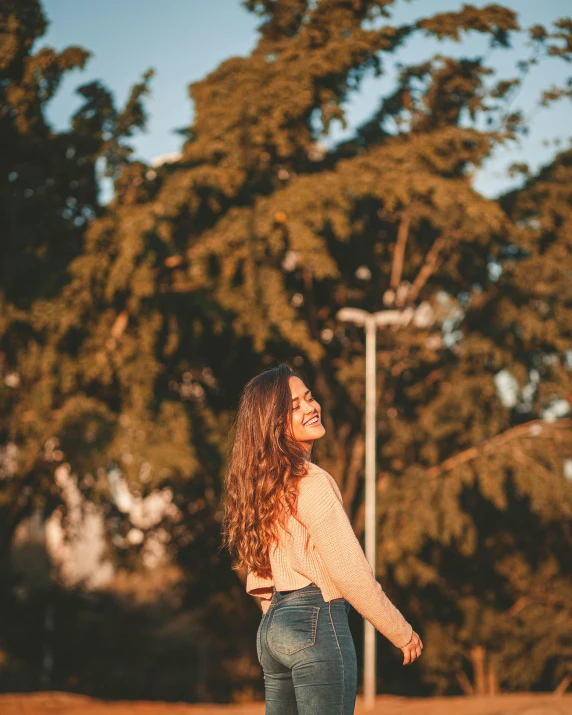 young woman standing in front of a parking lot and street light smiling