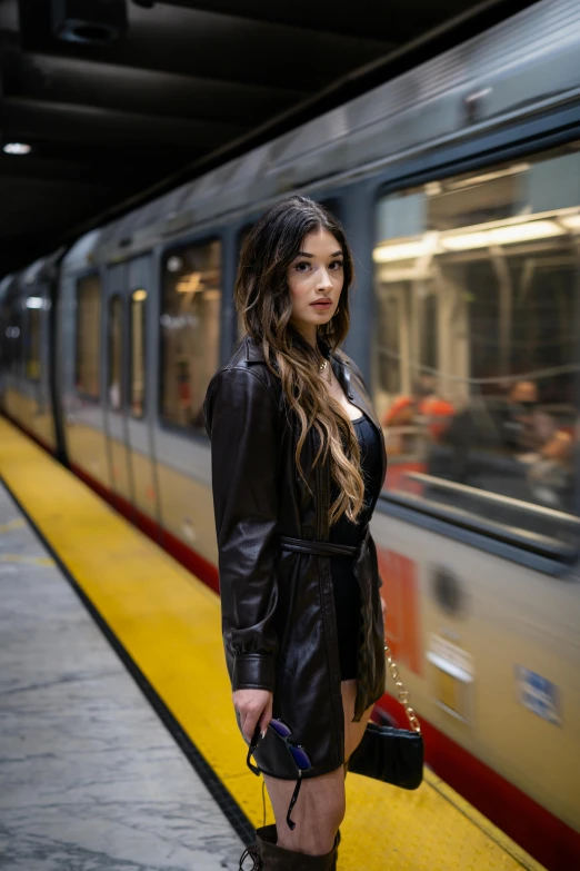 a young woman is standing on a platform next to a train