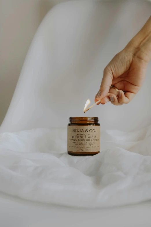 a person uses a candle as a touch to the jar