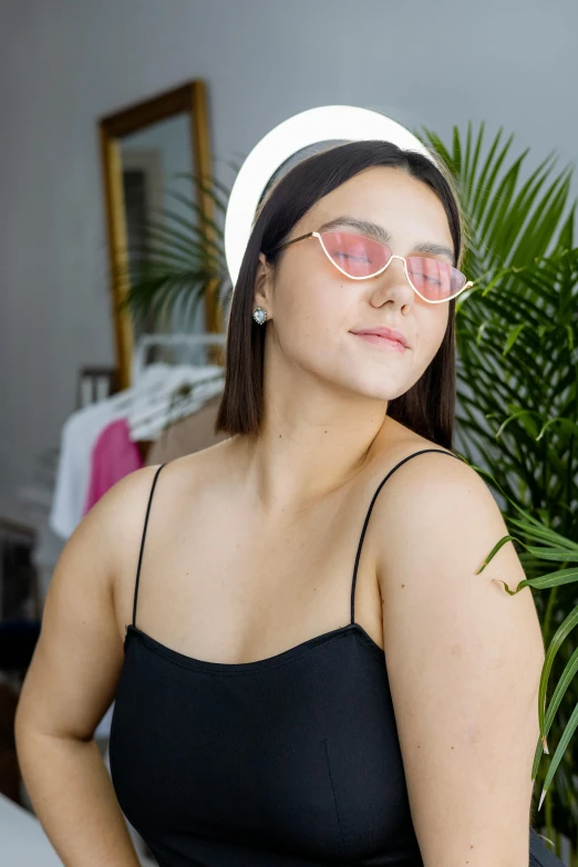 a woman with sunglasses sitting by a plant