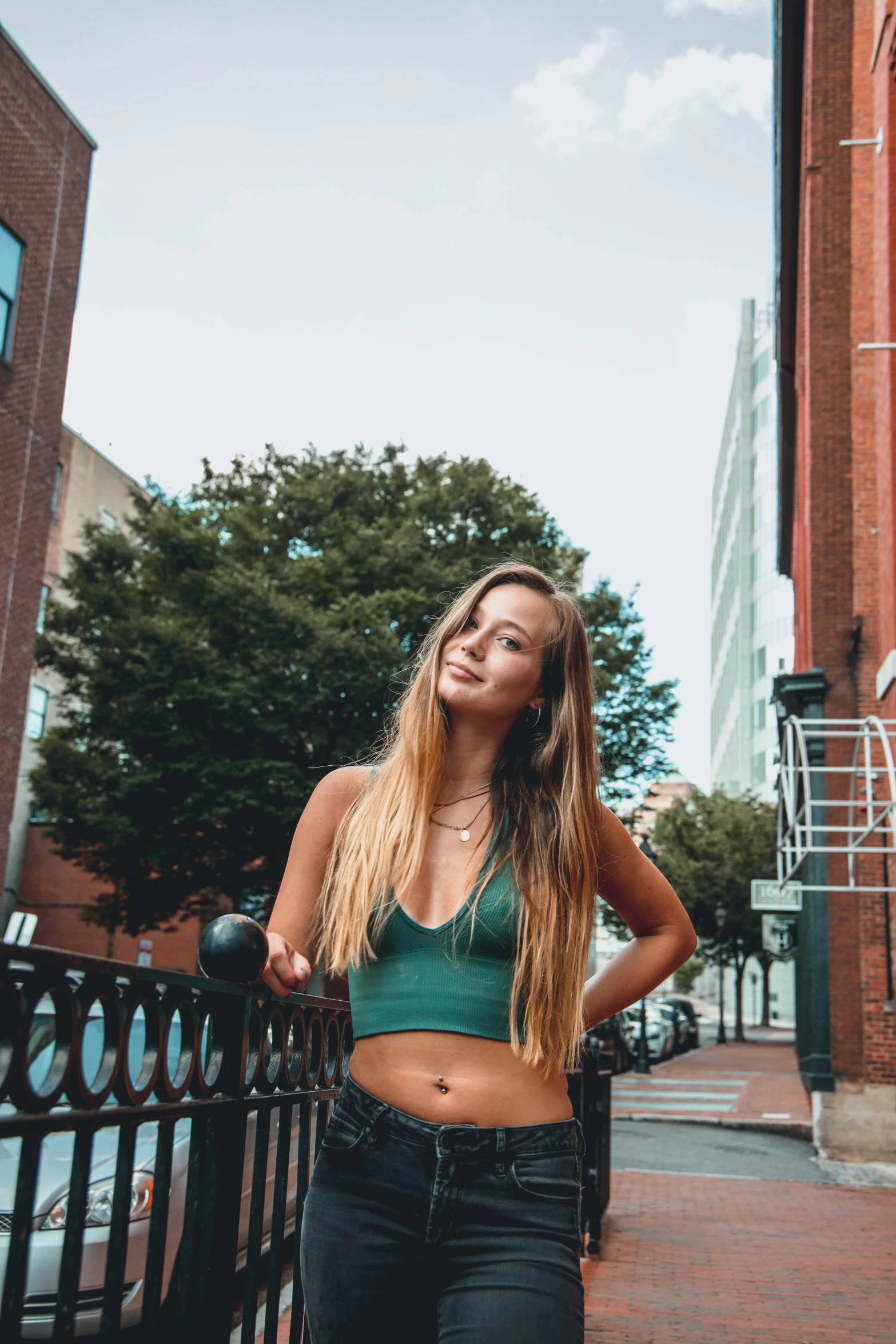 a beautiful woman in a green crop top posing by a fence