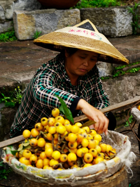 a woman wearing a hat reaching for fruit from a container