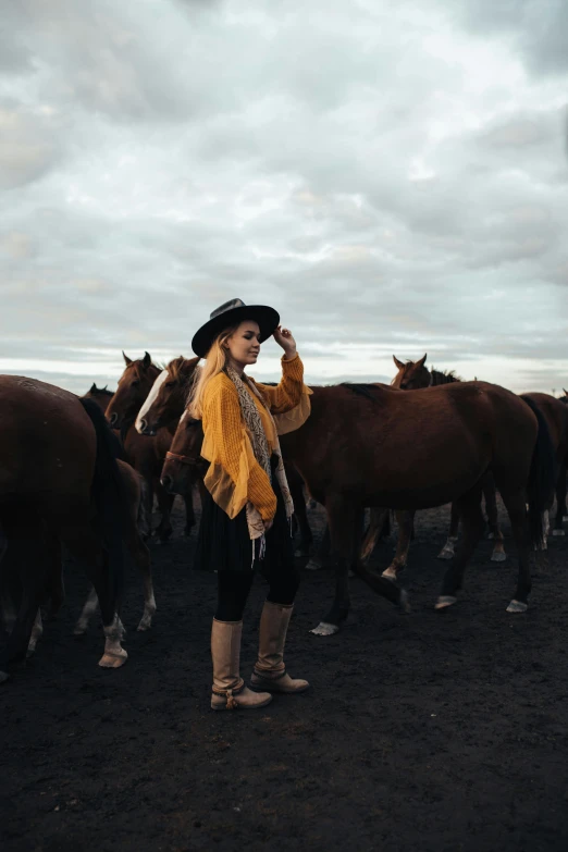 a woman standing in front of several horses