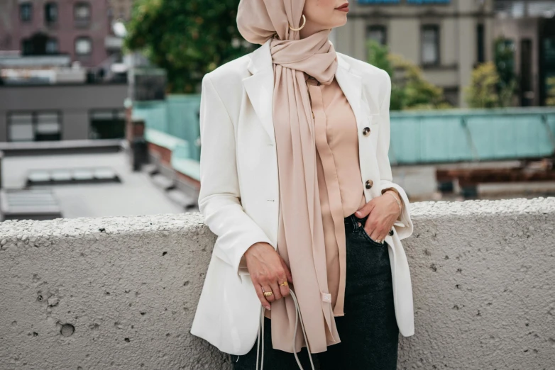 a woman leaning against a wall with a scarf