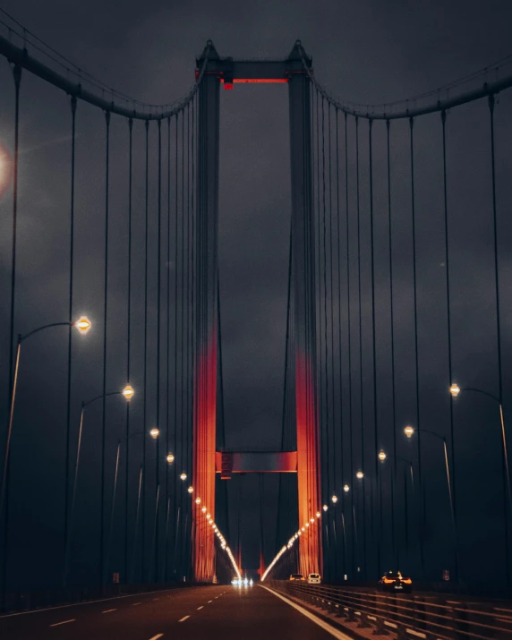 traffic passing over the top of an illuminated suspension bridge at night