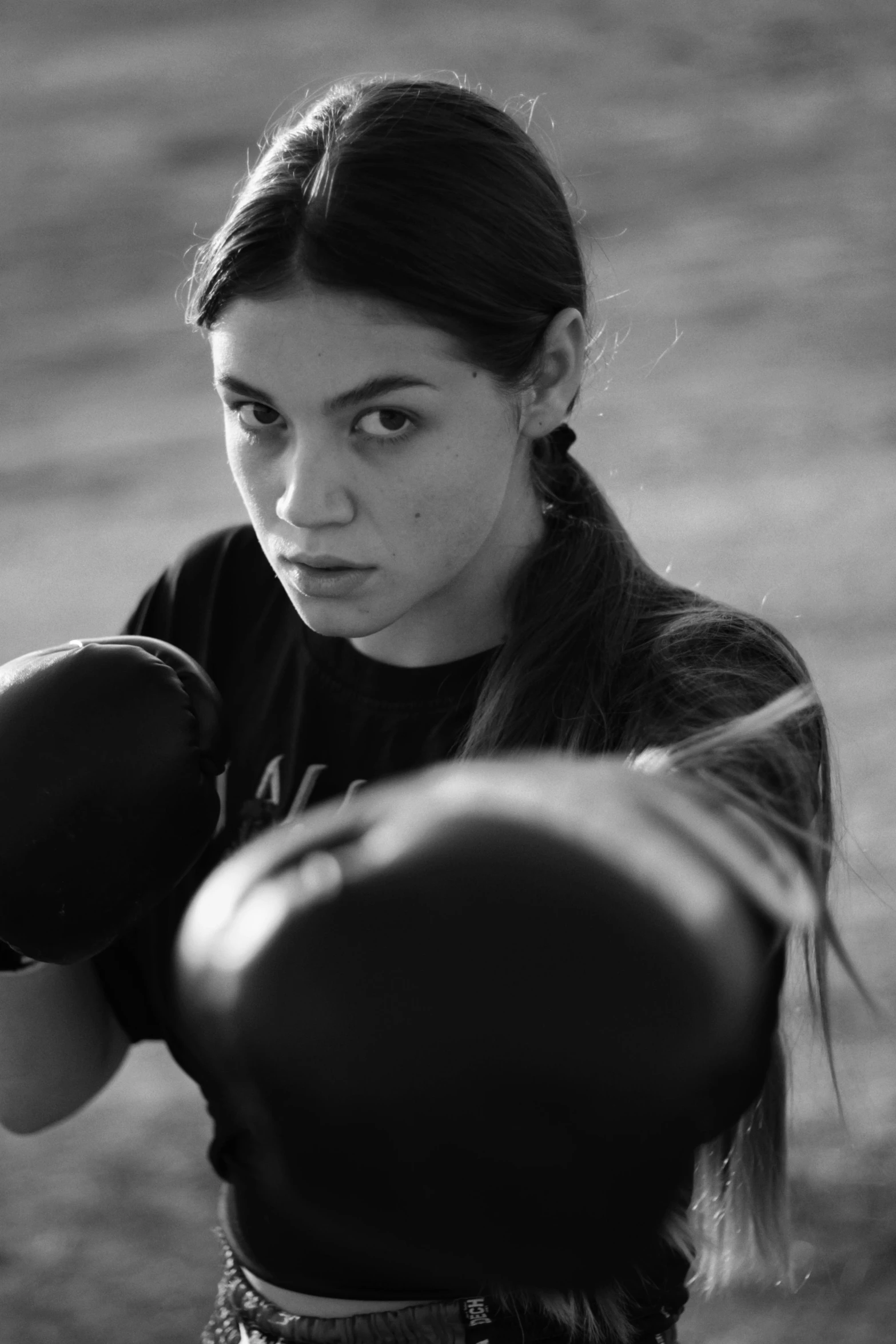 a woman with long dark hair, standing next to a boxing bag