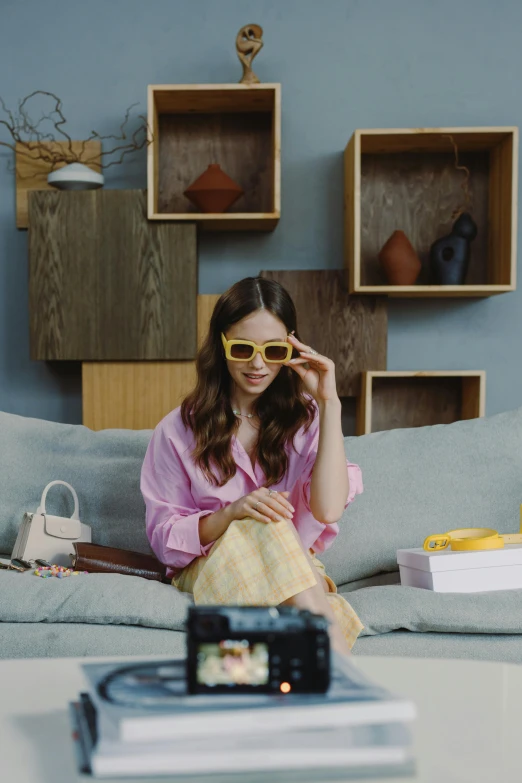 a woman wearing sunglasses is on the couch in her living room