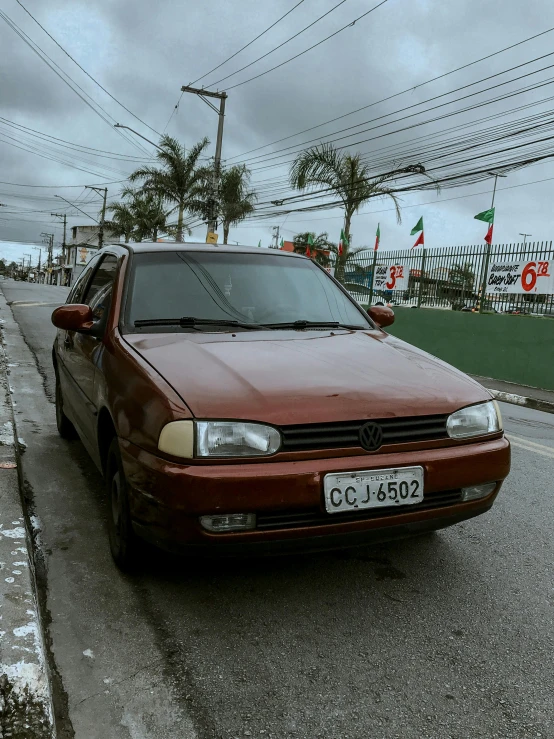 a red car parked on the side of a road next to power lines