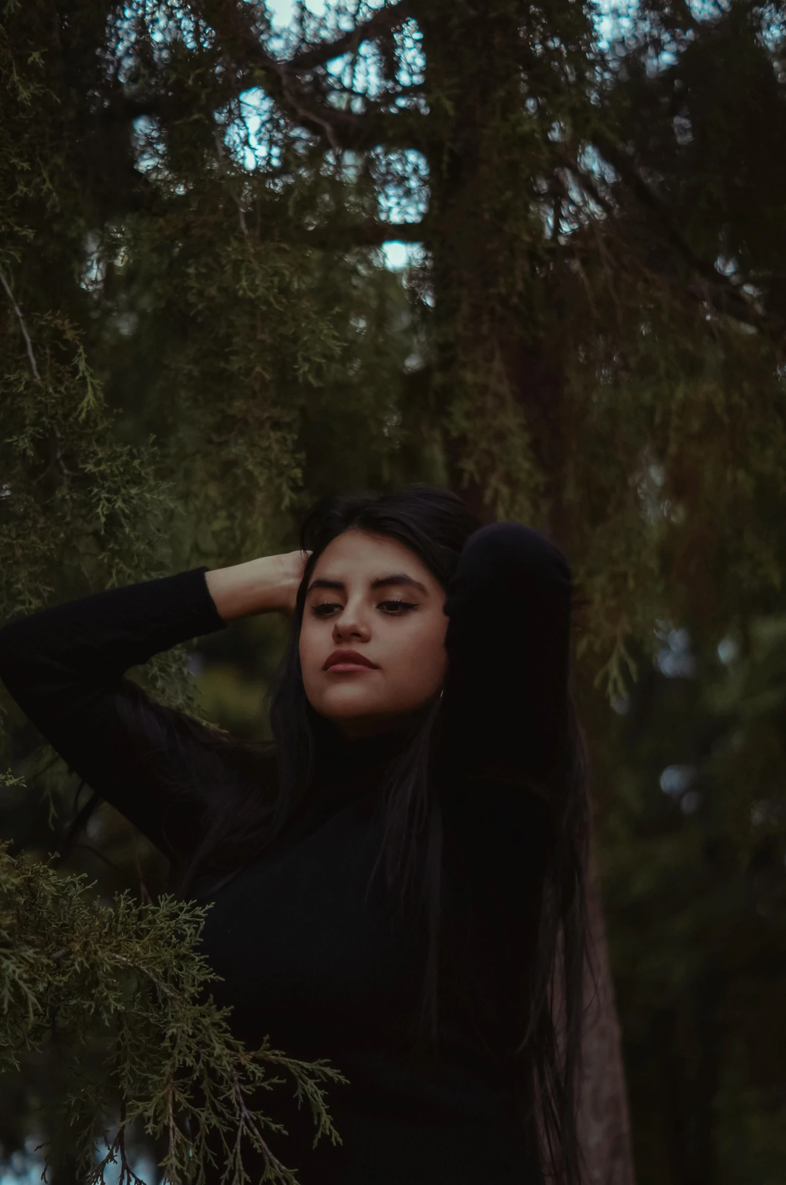 a woman is wearing long hair in the woods