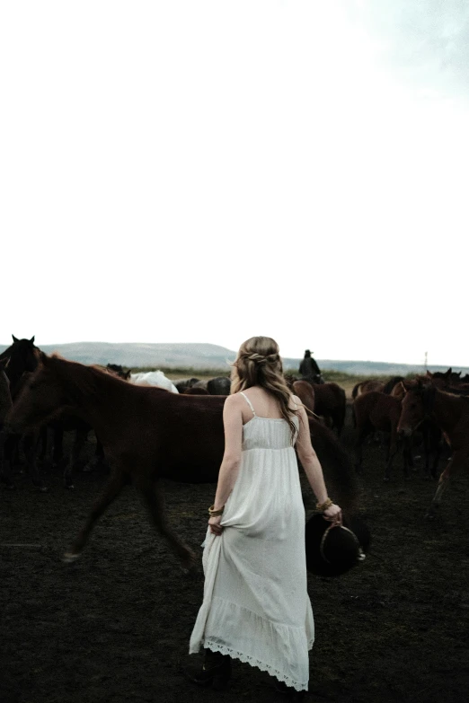 a girl in white walks toward some cows