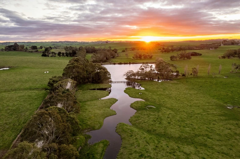 a view of a lake and green grass with a sunset in the background