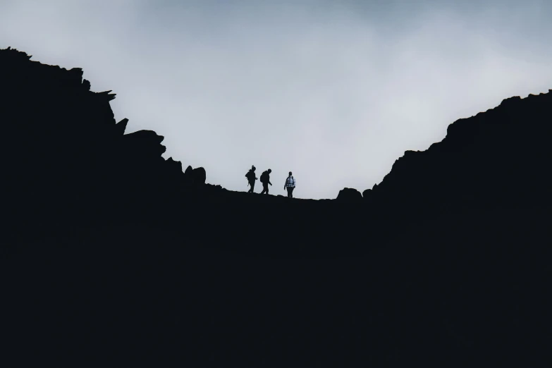 a silhouette of people on a steep cliff