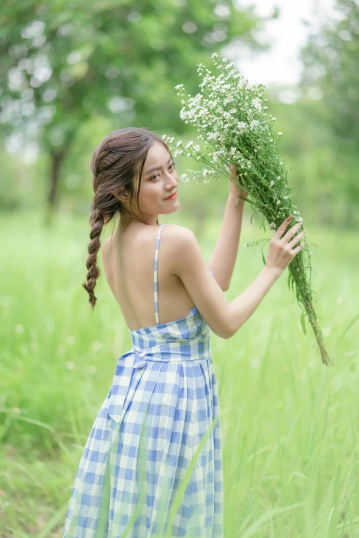 an asian girl holding plants in her hands and walking through tall grass