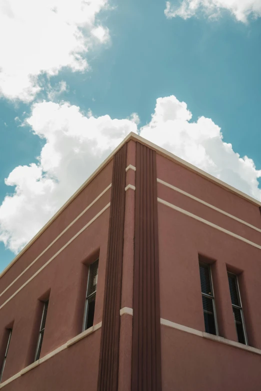 a building with large windows on the side and clouds in the background