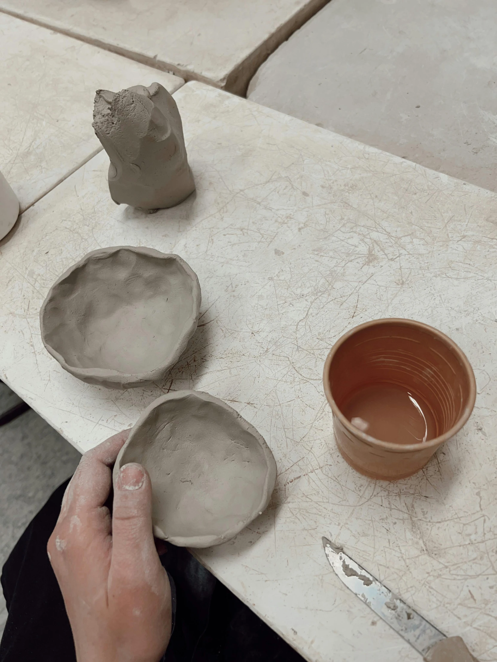 a person holding up two bowls and some tools on top of a table