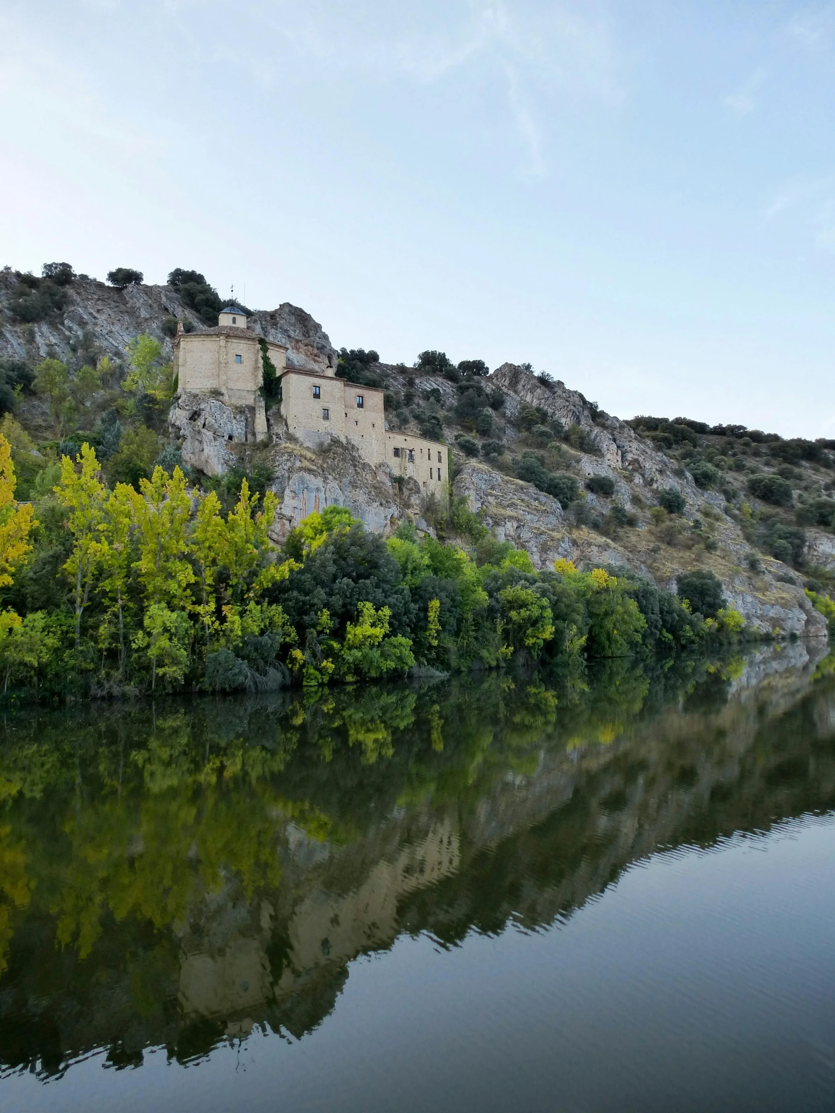 some buildings on a hill over water and trees