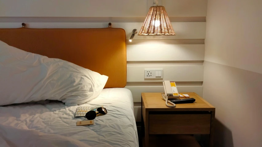 the lamp is shining above the bed with books and some sunglasses on it