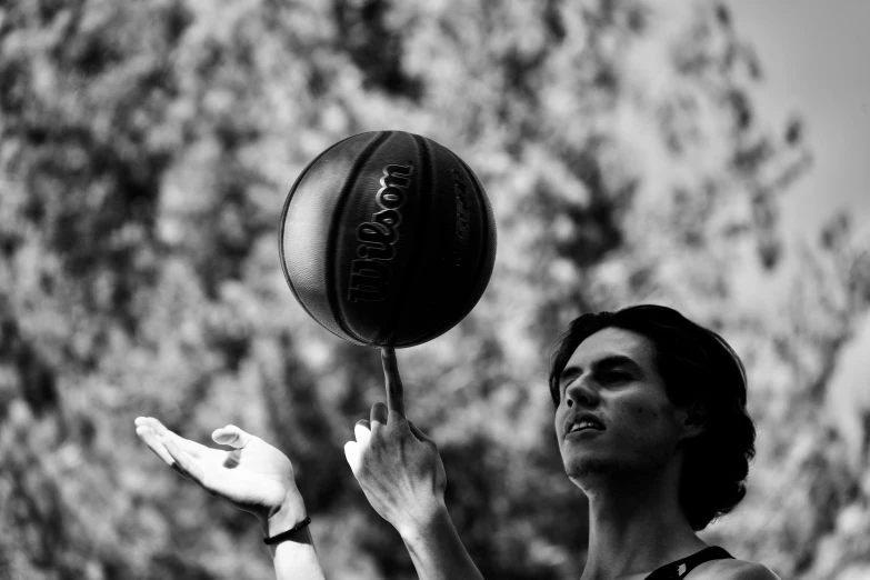 a black and white po of a lady spinning a basketball on her finger