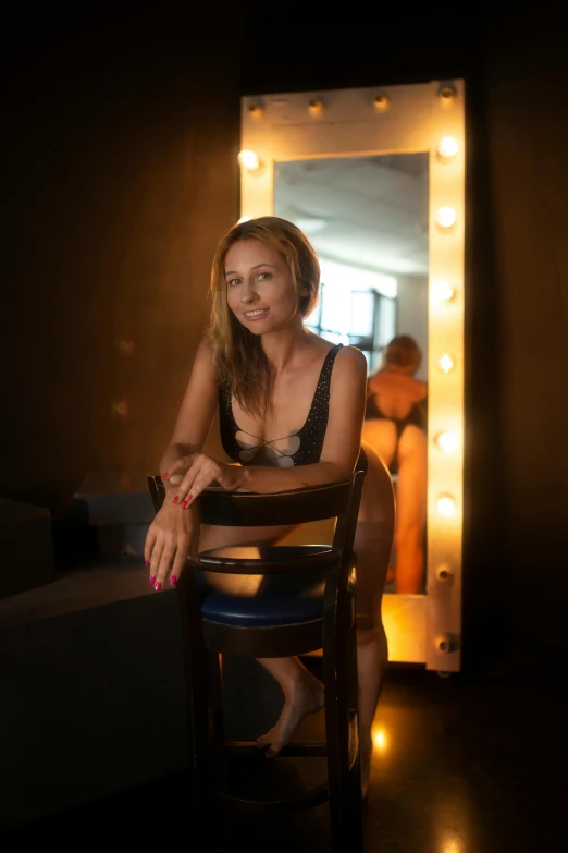 a smiling young woman sitting on a wooden chair