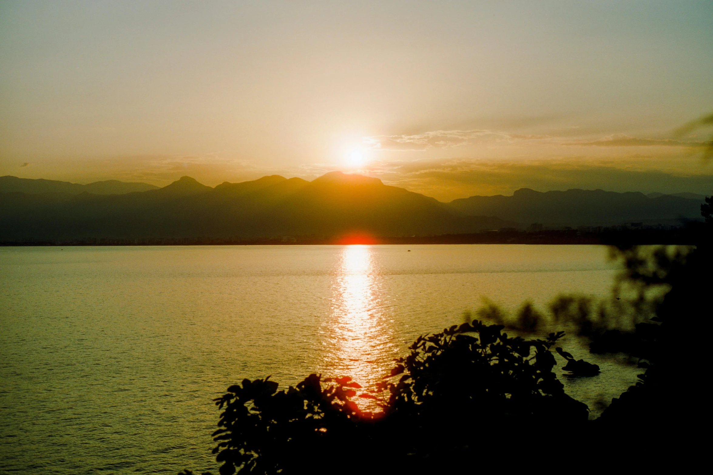 sun set behind mountains in front of the ocean